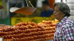 A woman buys tomatoes at a popular market in Caracas on October 24, 2013.