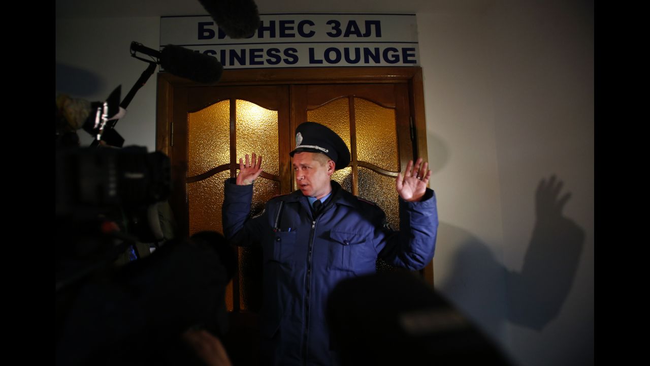 A Ukrainian police officer gives instructions to members of the media in front of the business class lounge of the Simferopol airport on March 5.