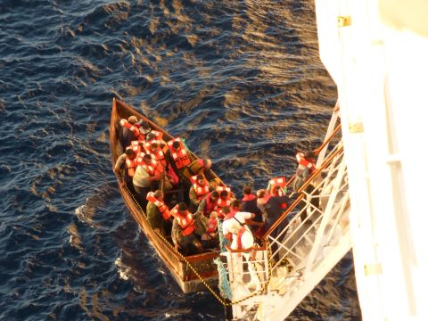 iReporter Matthew Sudder leaned over the railing of the Paradise to get this shot of the boat's passengers boarding the ship, wearing  life jackets provided by the ship's crew. They were given water, food, clothing, accommodations and medical care.