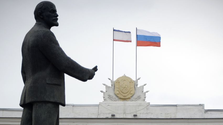 Russian (R) and Crimean flags flutter on top of the Crimean government building near a statue of Vladimir Lenin in Simferopol on March 4, 2014. Fears of an assault by Russian forces on Ukrainian military bases surrounded in Crimea did not materialise overnight, a Ukrainian defence ministry spokesman said Tuesday. 'The night was quiet,' Vladyslav Seleznyov, the defence ministry spokesman for Crimea, told AFP in the regional capital Simferopol. AFP PHOTO / ALEXANDER NEMENOV (Photo credit should read ALEXANDER NEMENOV/AFP/Getty Images)