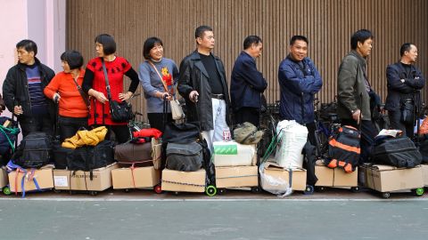 Visitors from mainland China wait in a queue with their goods outside the Sheung Shui train station in Hong Kong 