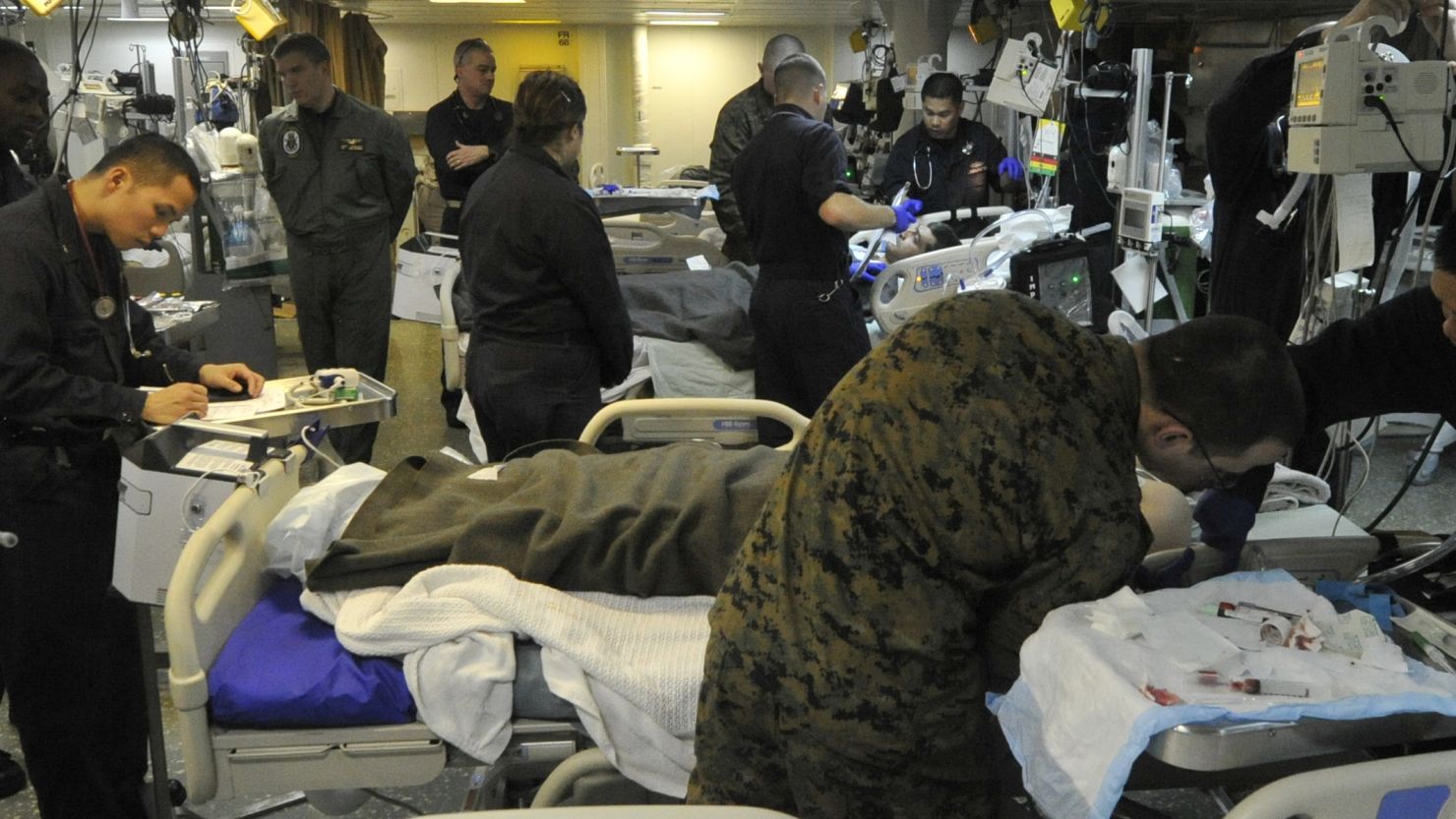 Medical personnel aboard the USS Bataan examine Turkish mariners rescued by a search and rescue swimmer.