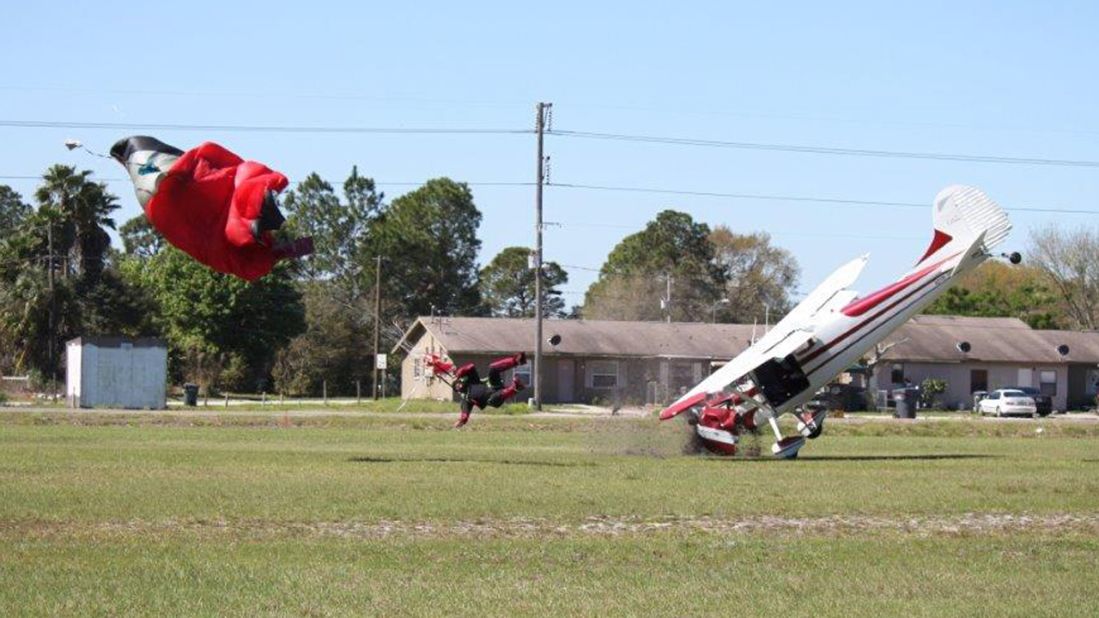 The plane crashes nose first into the ground after hitting the parachute.