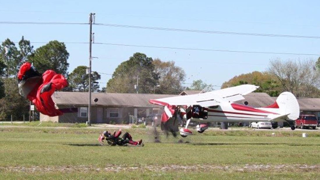 The Cessna lands upright beside the skydiver on the ground.