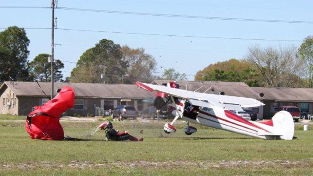 The skydiver sits up after crashing to the ground.