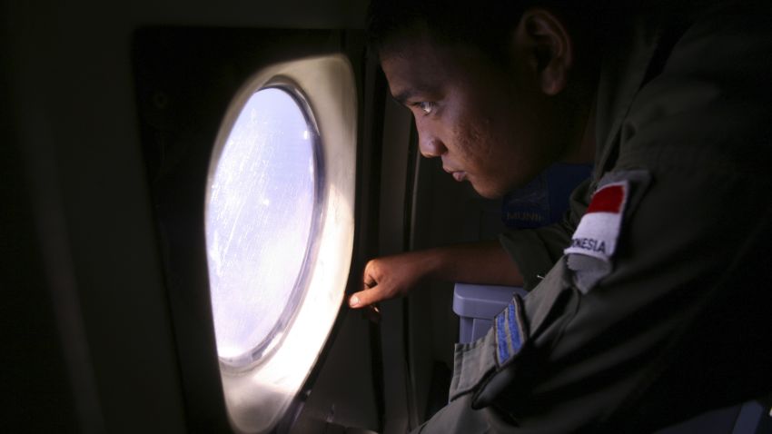 An Indonesian Navy crew member scans the water bordering Indonesia, Malaysia and Thailand during a search operation for the missing Malaysian Airlines Boeing 777 near the Malacca straits on Monday, March 10, 2014.