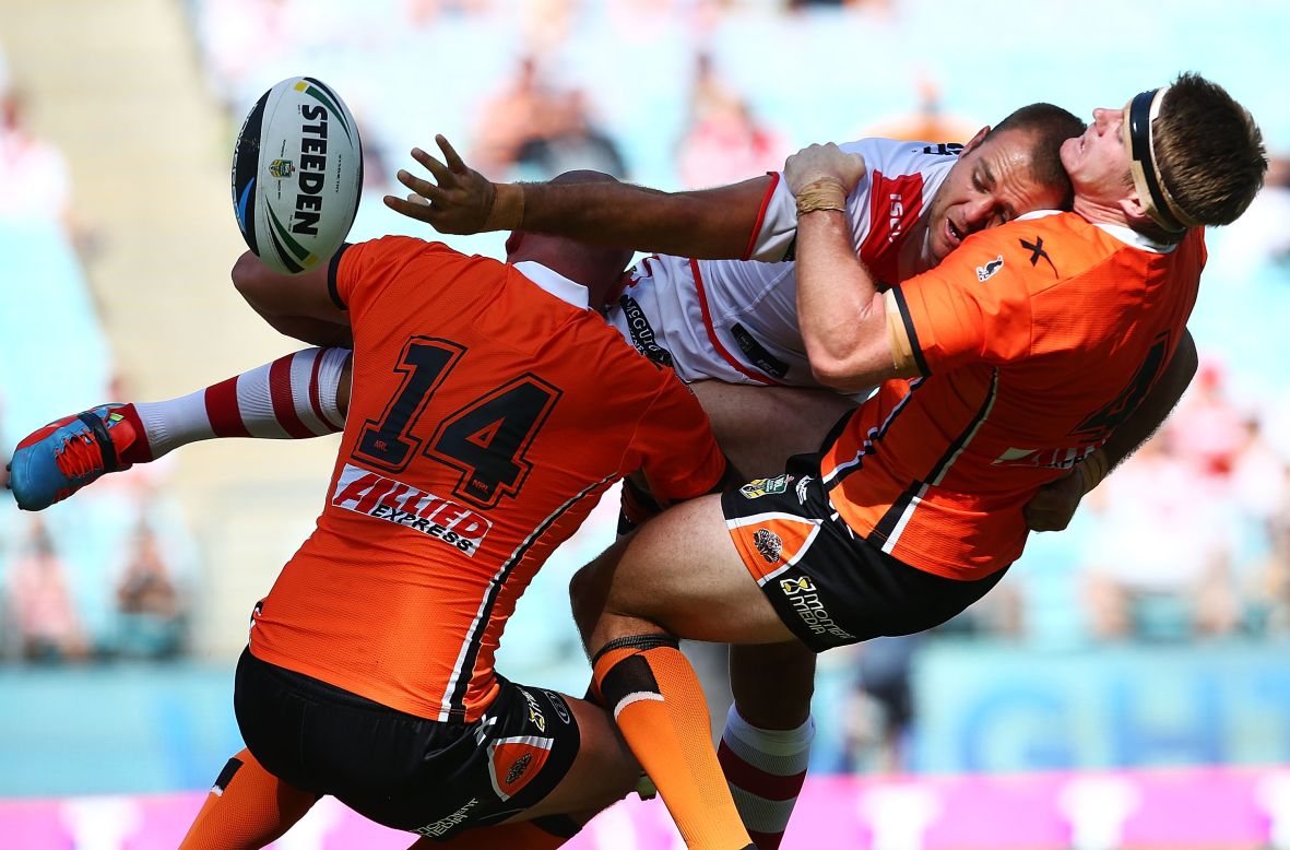 Jason Nightingale of the St. George Illawarra Dragons offloads the ball as he is smashed by two members of the Wests Tigers during a rugby league match Sunday, March 9, at the ANZ Stadium in Sydney.