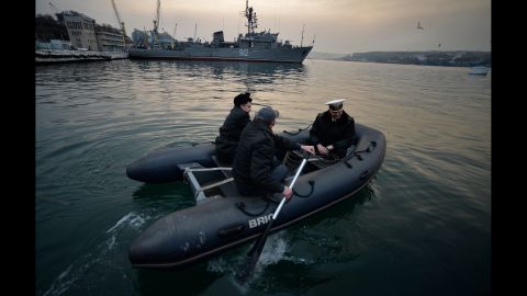 Ukrainian naval officers board a boat in front of the Russian minesweeper Turbinist in Sevastopol's harbor on March 11.