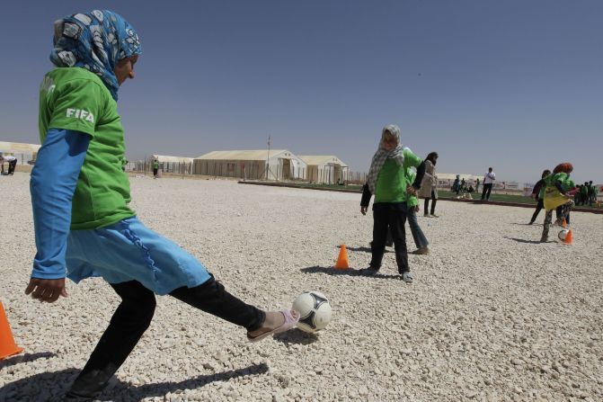 A group of young girls wearing one of the FIFA shirts enjoy kicking a ball.