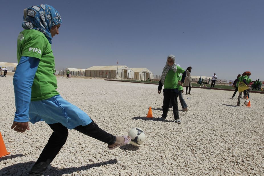 A group of young girls wearing one of the FIFA  shirts enjoy kicking a ball.