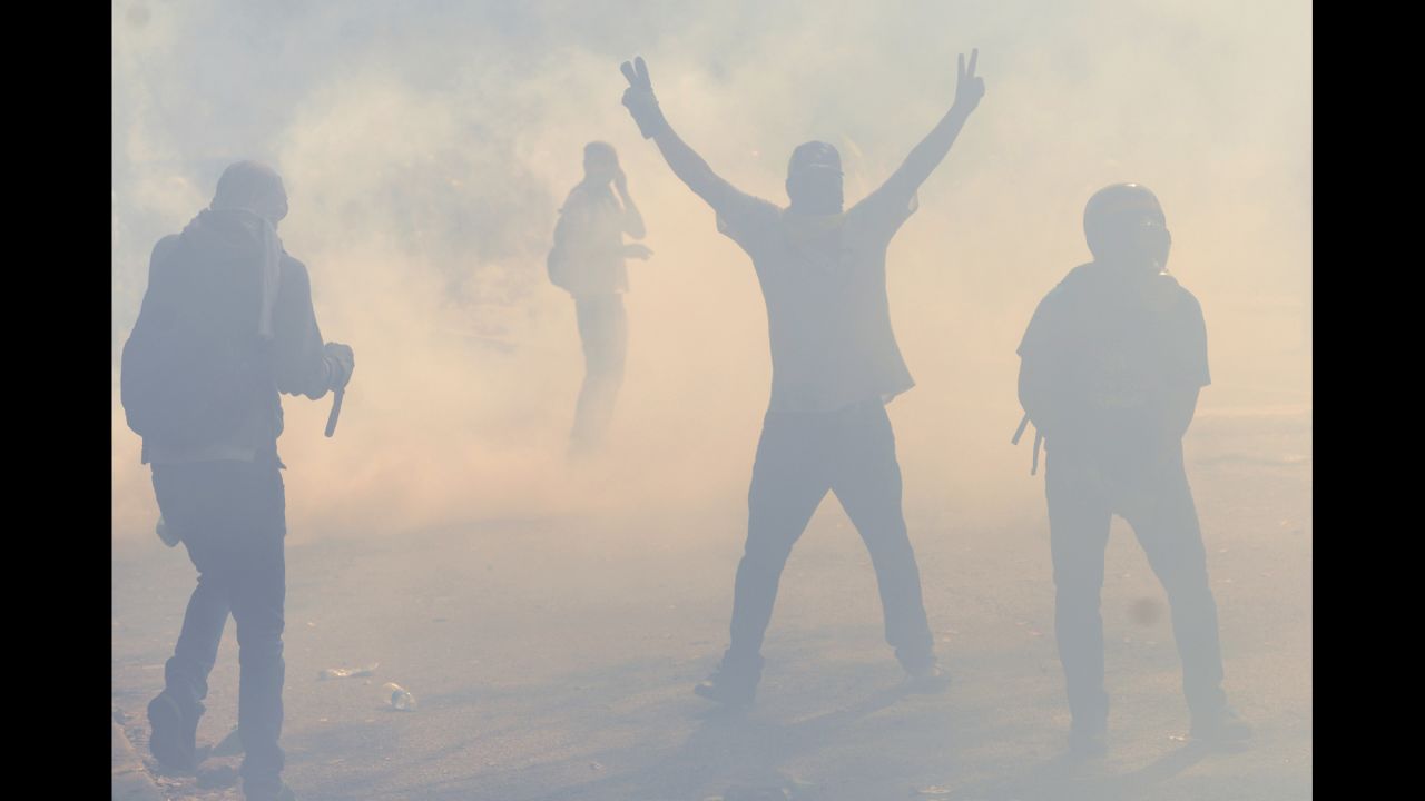 Students walk amid tear gas shot by riot police in Caracas on March 12.