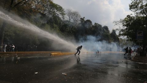 Protesters run from a water cannon blast shot by police in Caracas on March 12.