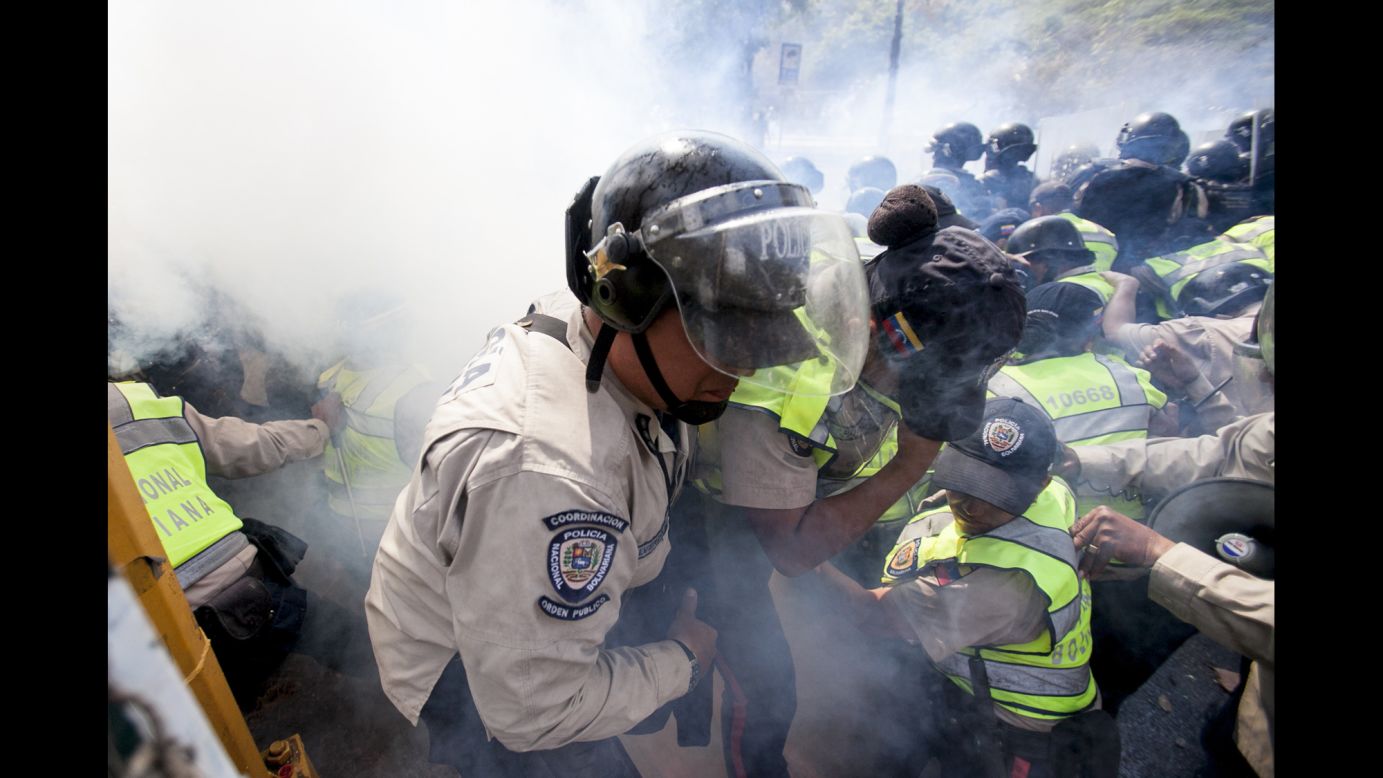 A police officer is removed from the front line of clashes after being overwhelmed by tear gas in Caracas.