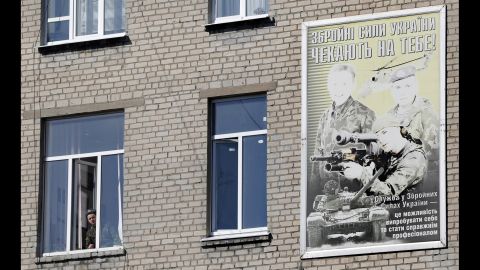 A Ukrainian soldier looks out of the window of a regional military building with a poster reading "Ukraine's armed forces wait for you!" in Donetsk on March 13.