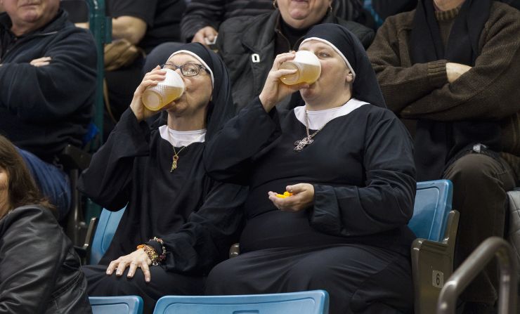 Two women wearing nun outfits drink beer while they watch curling Saturday, March 8, in Kamloops, British Columbia. 