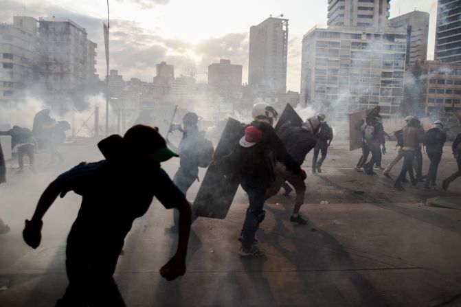 Anti-government protesters take cover from tear gas during clashes with police Monday, March 10, in Caracas, Venezuela. It has been a month since <a href="http://www.cnn.com/2014/02/18/world/gallery/venezuela-protests/index.html">violent clashes in the country</a> first grabbed global attention, and demonstrators have shown no sign of backing down.