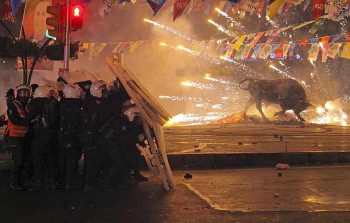 Riot police in Istanbul shield themselves as fireworks thrown by anti-government protesters explode next to a statue of a bull on Tuesday, March 11. Protesters clashed with police across Turkey after <a href="http://www.cnn.com/2014/03/13/world/europe/turkey-shooting-death/index.html">the death of Berkin Elvan</a>, a 15-year-old boy who was critically wounded nine months ago after apparently being hit by a tear gas canister.