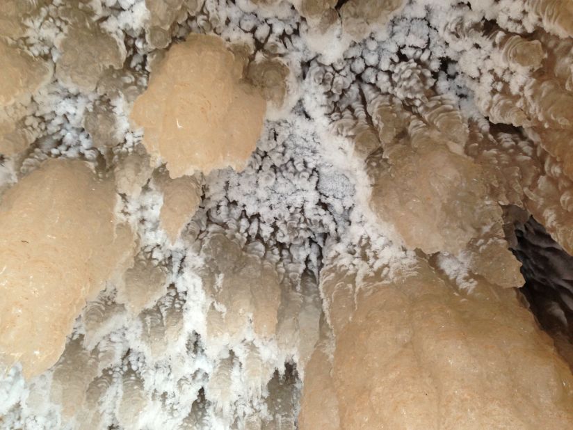 White- and gold-colored icicles form out of a brown sandstone cave over the frozen waters of Lake Superior.