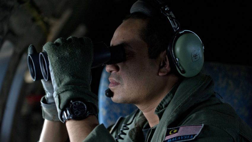 Caption: A crew member uses binoculars onboard a Malaysian Air Force CN235 aircraft during a search and rescue (SAR) operation to find the missing Malaysia Airlines flight MH370 plane over the Strait of Malacca on March 14, 2014. Malaysia confirmed on March 14 that the search for a missing Malaysia Airlines plane had been expanded into the Indian Ocean, but declined to comment on US reports that the jet had flown for hours after going missing. AFP PHOTO / MOHD RASFANMOHD RASFAN/AFP/Getty Images