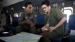 TO GO WITH: MALAYSIA-CHINA-VIETNAM-MALAYSIAAIRLINES-TRANSPORT-ACCIDENT,FOCUS BY SHANNON TEOH 
This picture taken on March 15, 2014 shows Royal Malaysian Air Force Navigator captain Izam Fareq Hassan (L) explaning to Agence France-Presse correspondent Shannon Teoh on board a Malaysian Air Force CN235 during a search and rescue (SAR) operation to find the missing Malaysia Airlines flight MH370 plane over the Strait of Malacca. The disappearance of a Malaysia Airlines passenger jet is a potential disaster for a national flag carrier already struggling to cauterise severe financial hemorrhaging in the face of intensifying industry competition, raising the spectre of costly lawsuits and a drop in bookinngs. AFP PHOTO / MOHD RASFANMOHD RASFAN/AFP/Getty Images