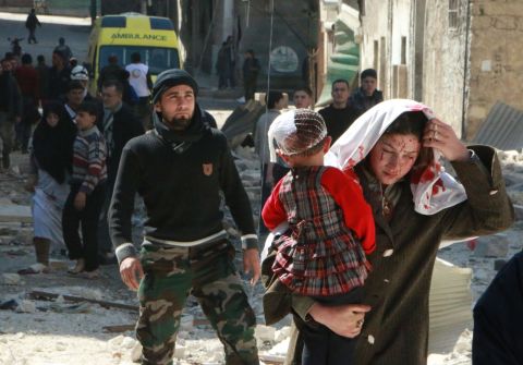 A woman with blood on her face carries a child following a reported airstrike by government forces Saturday, March 15, in Aleppo.