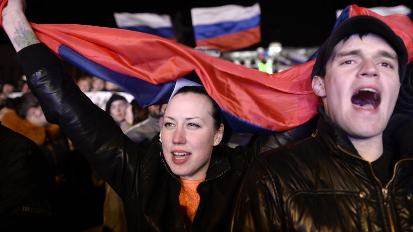 People sing the Russian national anthem as they celebrate in Simferopol's Lenin Square on March 16, 2014 after exit polls showed that about 95.5 percent of voters in Ukraine's Crimea region supported union with Russia. Crimeans voted overwhelmingly to join former political master Russia as tensions soared in the east of the splintered ex-Soviet nation amid the worst East-West crisis since the Cold War. AFP PHOTO / DIMITAR DILKOFF (Photo credit should read DIMITAR DILKOFF/AFP/Getty Images)