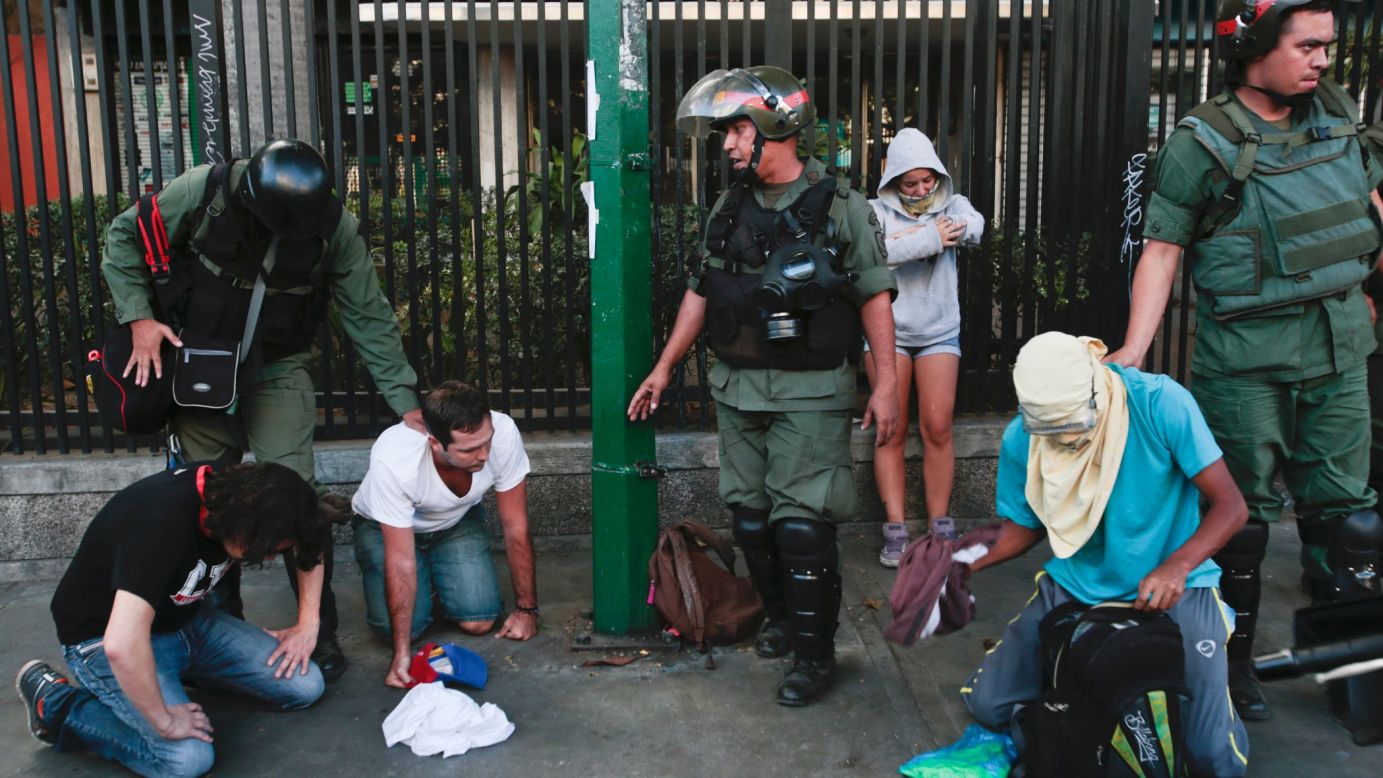 Anti-government protesters kneel as National Guardsmen arrest them in Caracas on March 16.
