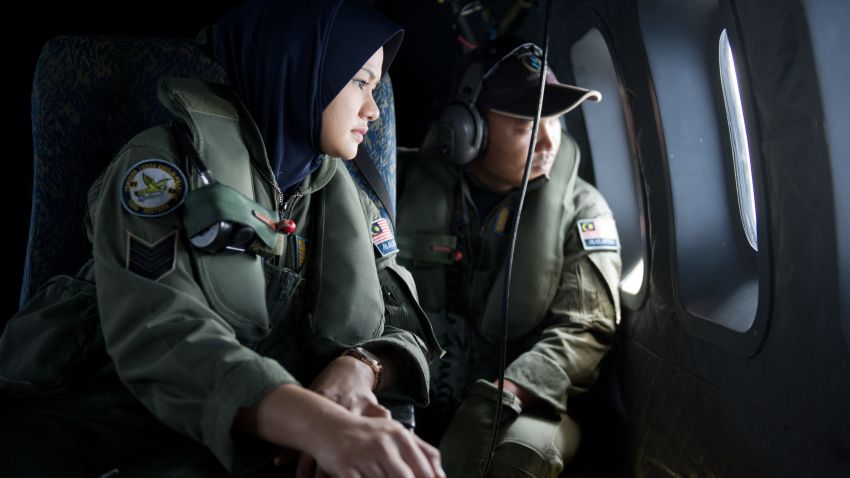 Crew members look outside windows from a Malaysian Air Force CN235 aircraft during a search and rescue (SAR) operation to find the missing Malaysia Airlines flight MH370 plane over the Strait of Malacca on March 15, 2014.