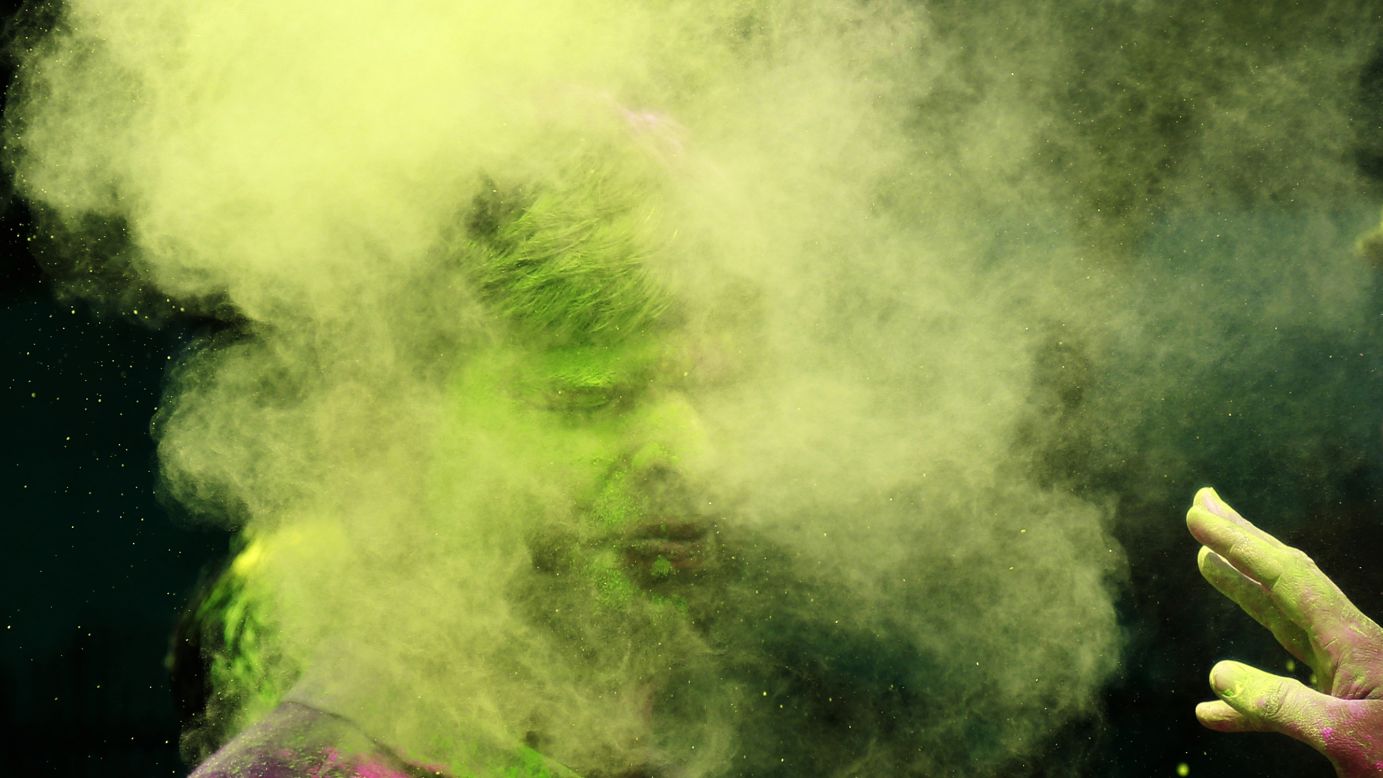 A man throws colored powder on another man March 17 in Mumbai.