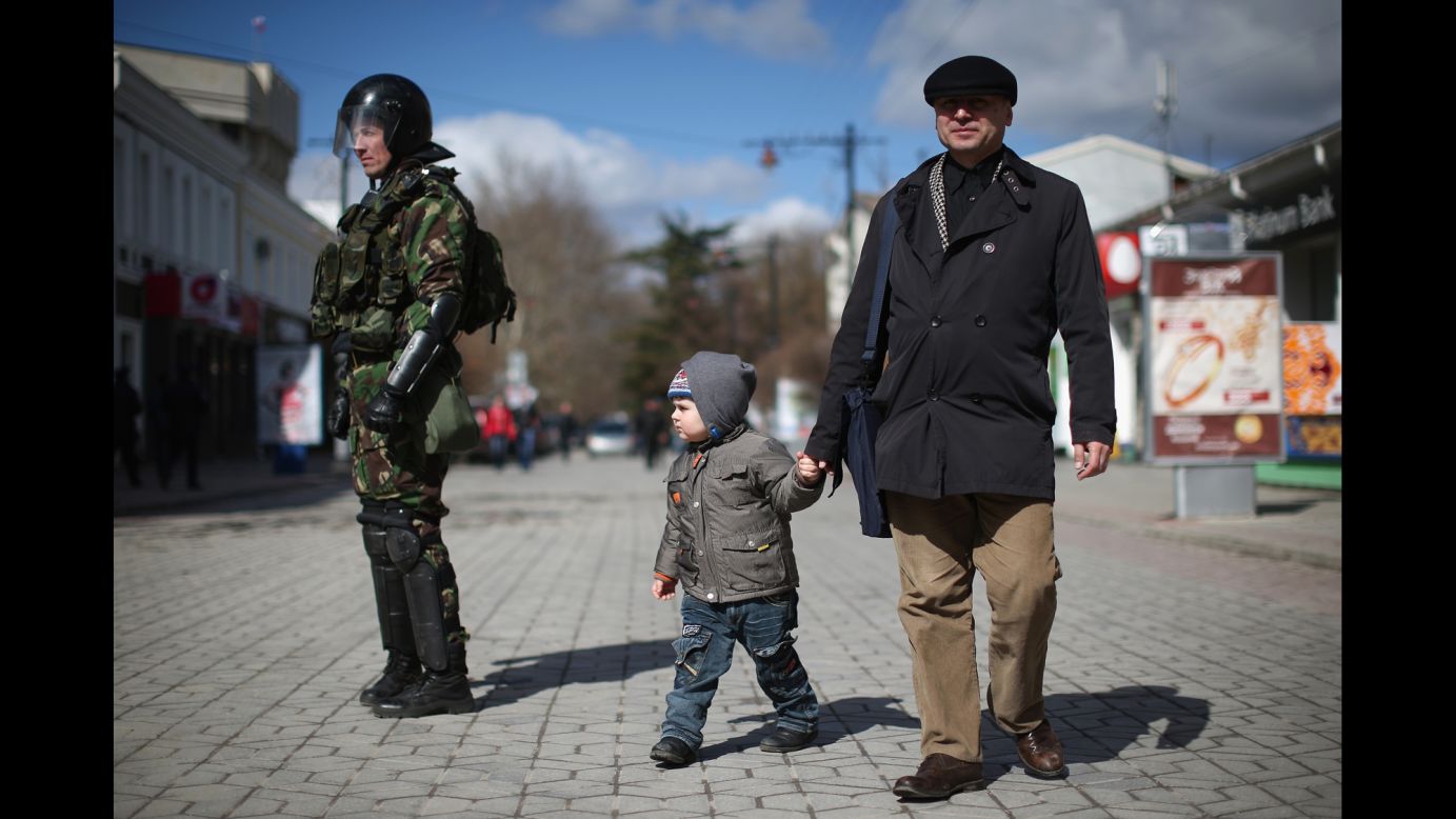 Civilians walk past riot police in Simferopol on March 17.