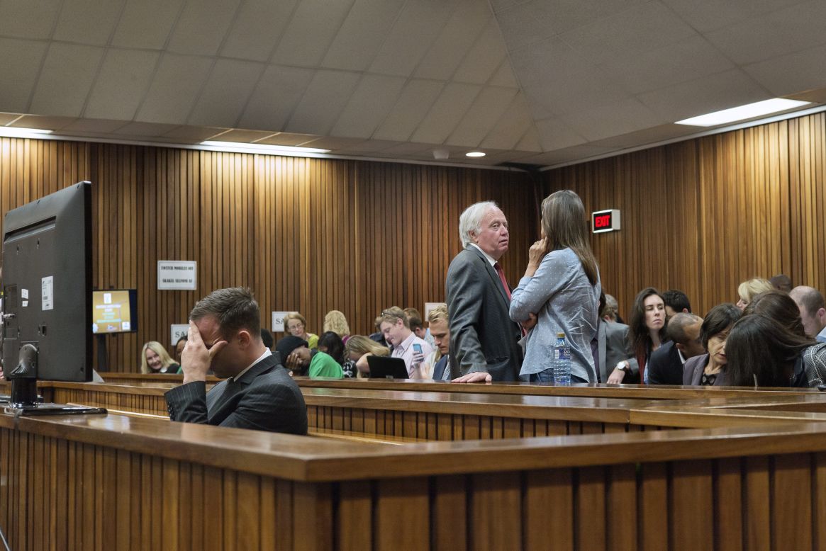 Pistorius holds his head while members of his family talk behind him on Tuesday, March 18.