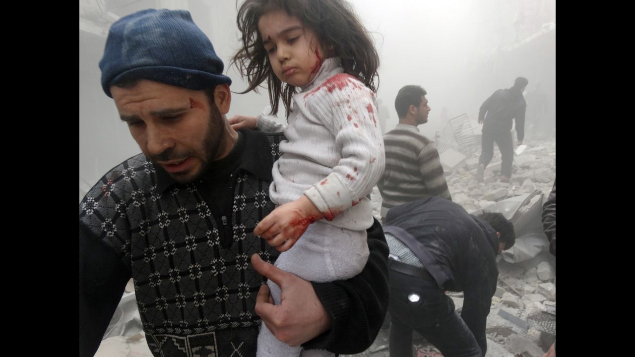 A man carries a child who was found in the rubble of an Aleppo building after it was reportedly bombed by government forces on Monday, March 18.