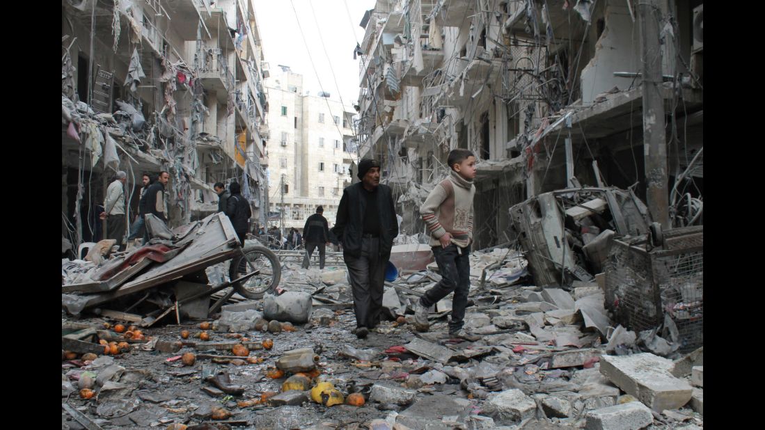An elderly man and a child walk among debris in a residential block of Aleppo on March 18. 
