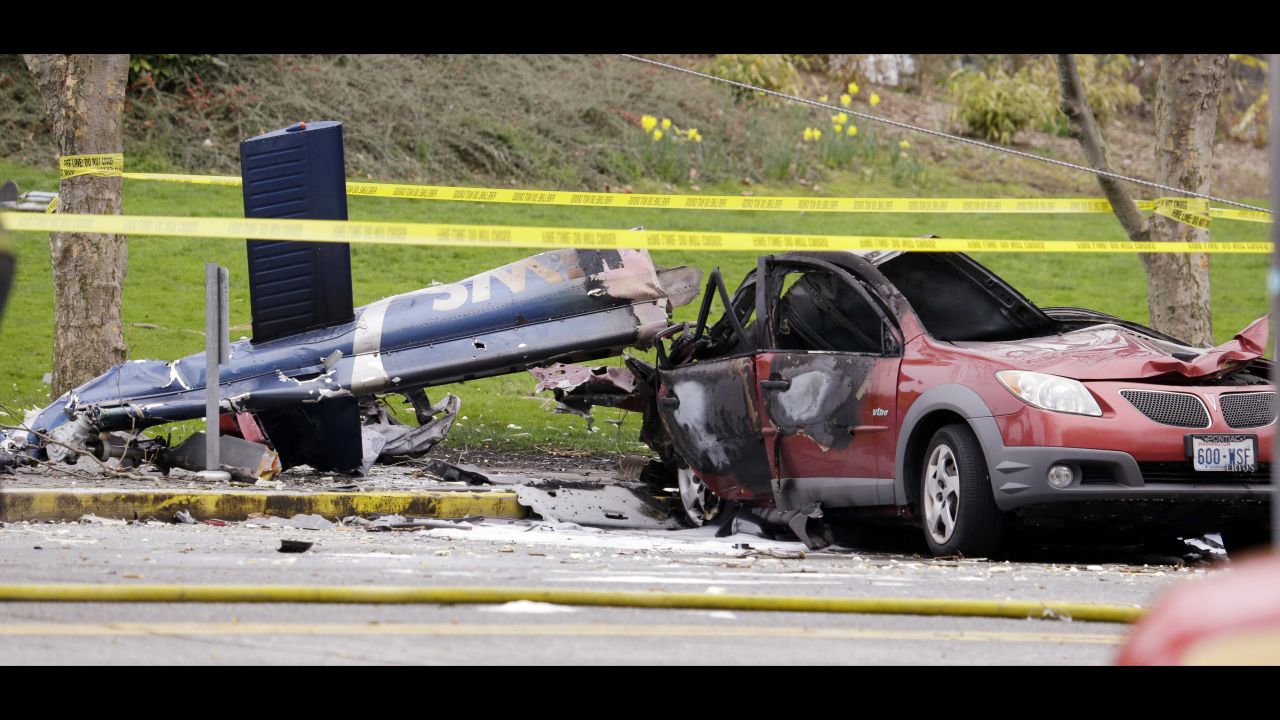 A burned car is seen next to a piece of the helicopter wreckage.