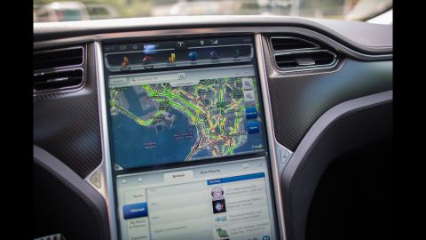 A Google map is displayed on a screen in a Tesla Model S sedan. 