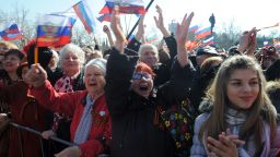 People react as they listen to a speech of Russian president broadcast on a giant screen in Sevastopol, on March 18, 2014.