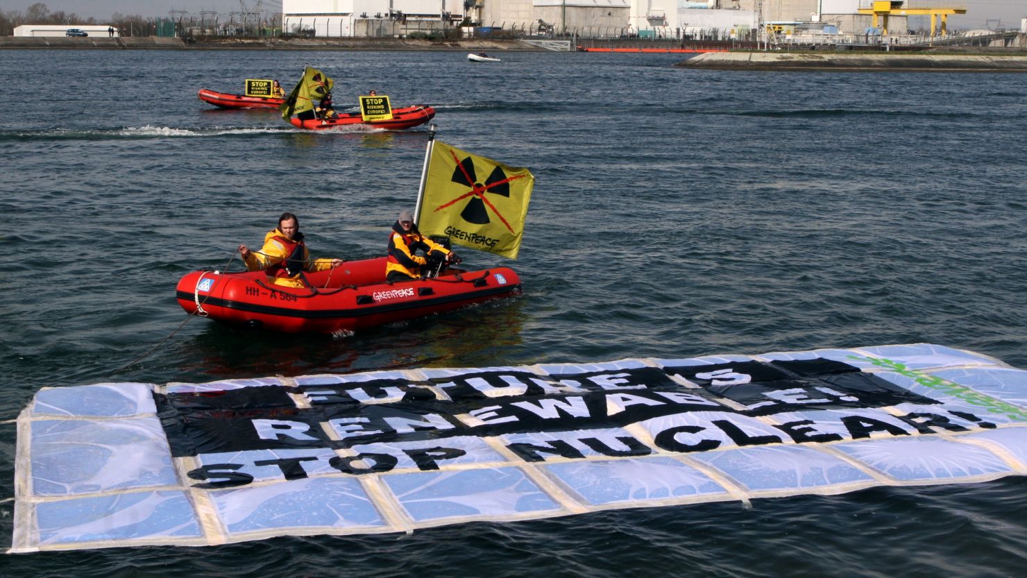 Greenpeace hold banners in boats in front of the nuclear power plant of Fessenheim on March 18, 2014.