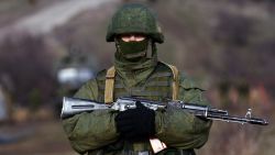An armed man, believed to be Russian serviceman, patrols outside an Ukrainian military base in Perevalnoye on March 17, 2014.