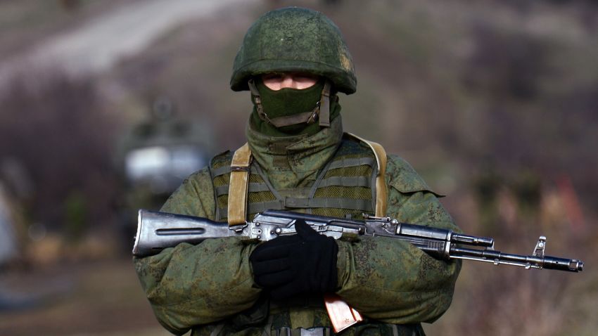 An armed man, believed to be Russian serviceman, patrols outside an Ukrainian military base in Perevalnoye on March 17, 2014.