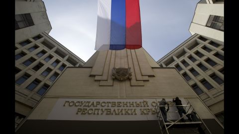 A Russian flag waves as workers install a new sign on a parliament building in Simferopol, Crimea's capital, on March 19.