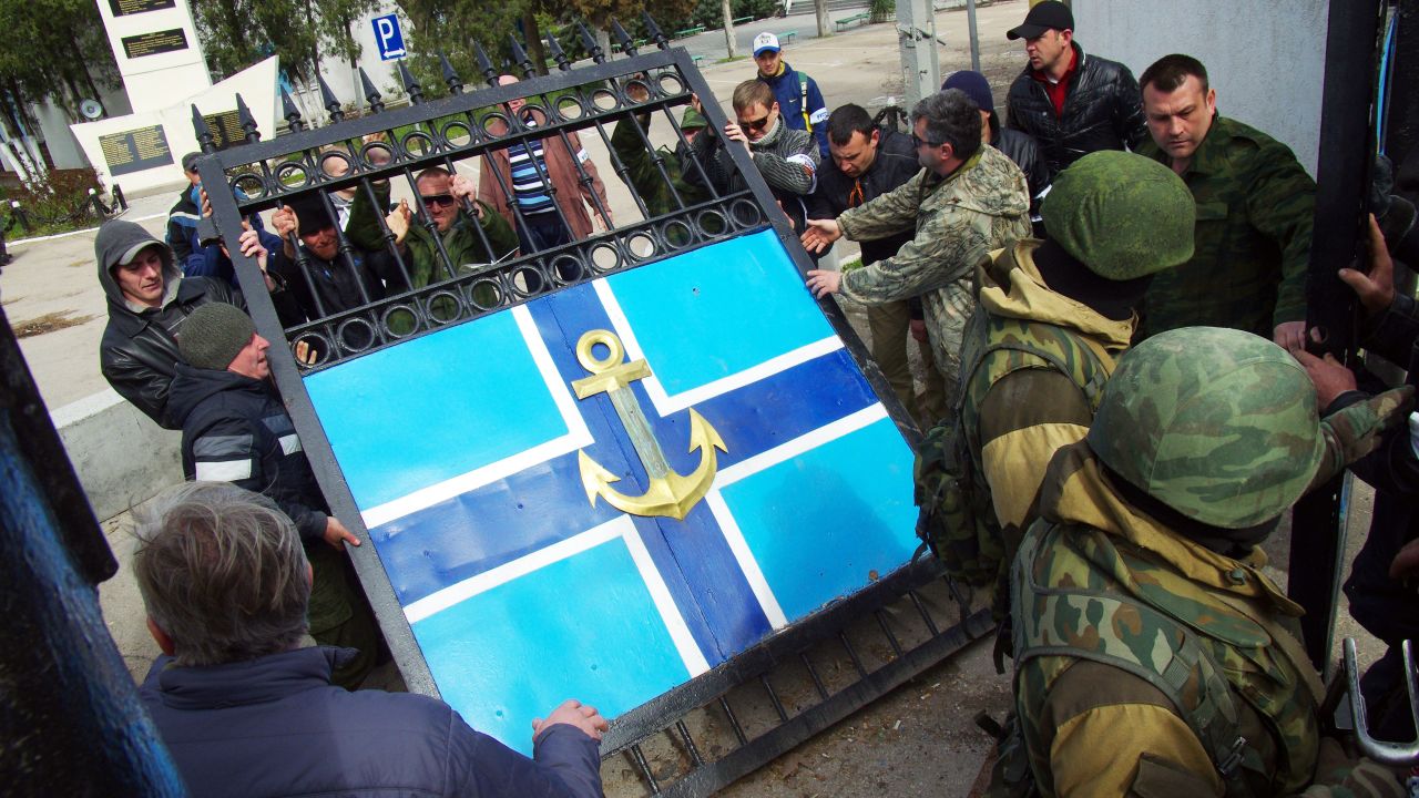 Pro-Russian protesters remove the gate to the Ukrainian navy headquarters as Russian troops stand guard in Sevastopol on Wednesday, March 19.