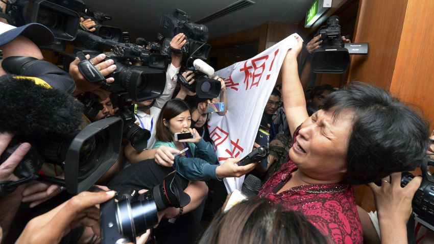 A Chinese relative of passengers aboard a missing Malaysia Airlines plane cries as she holds a banner in front of journalists reading 'We are against the Malaysian government for hiding the truth and delaying the rescue. Release our families unconditionally!"  at a hotel in Sepang, Malaysia, Wednesday, March 19, 2014. Malaysian authorities examined new radar data from Thailand that could potentially give clues on how to retrace the course of the Malaysia Airlines plane that vanished early March 8 with 239 people aboard en route from Kuala Lumpur to Beijing. Twenty-six countries are looking for the aircraft as relatives anxiously await news. (AP Photo) MALAYSIA OUT