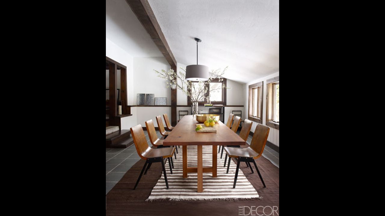 In the dining room: Vintage chairs from R. T. Facts surround the dining table, which was made from a cherry tree on the property; the light fixture is by Restoration Hardware, the rugs are Moroccan, and the flooring is slate.