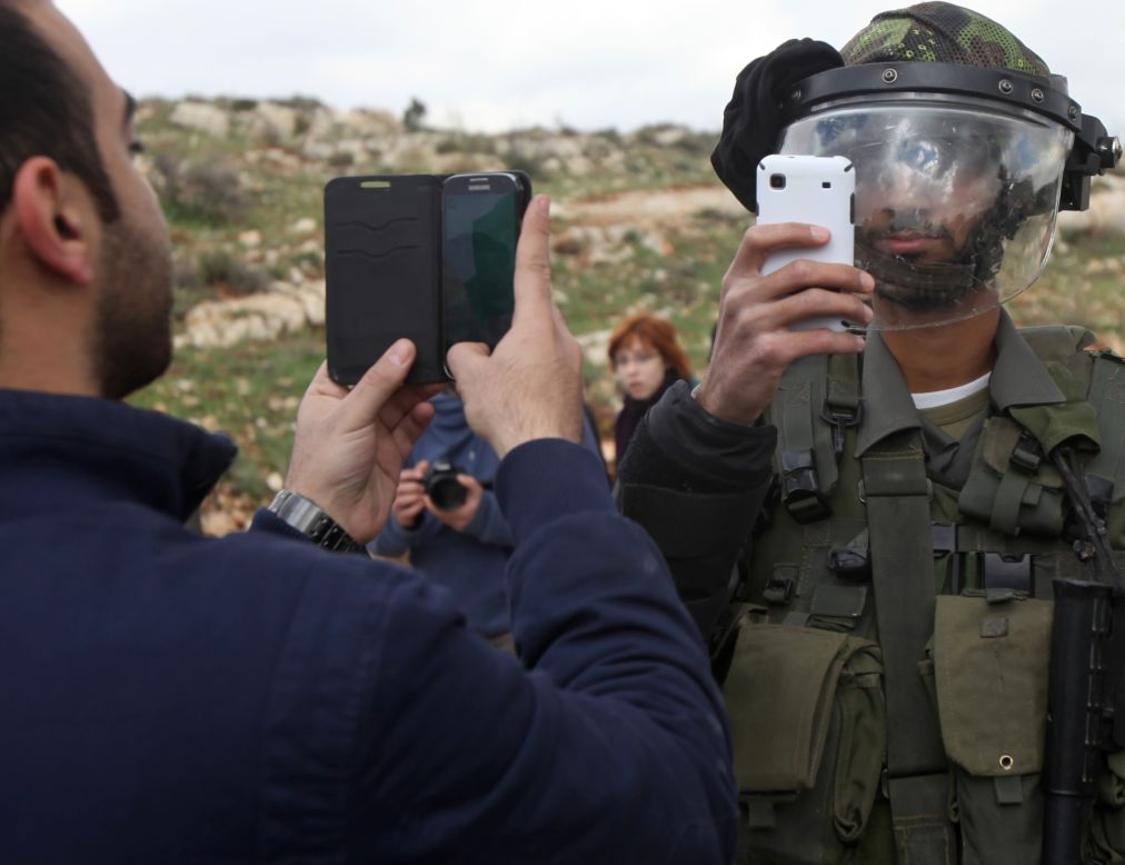 A Palestinian man and a member of Israel's security forces take pictures of each other Friday, March 14, after a demonstration in the West Bank village of Nabi Saleh.