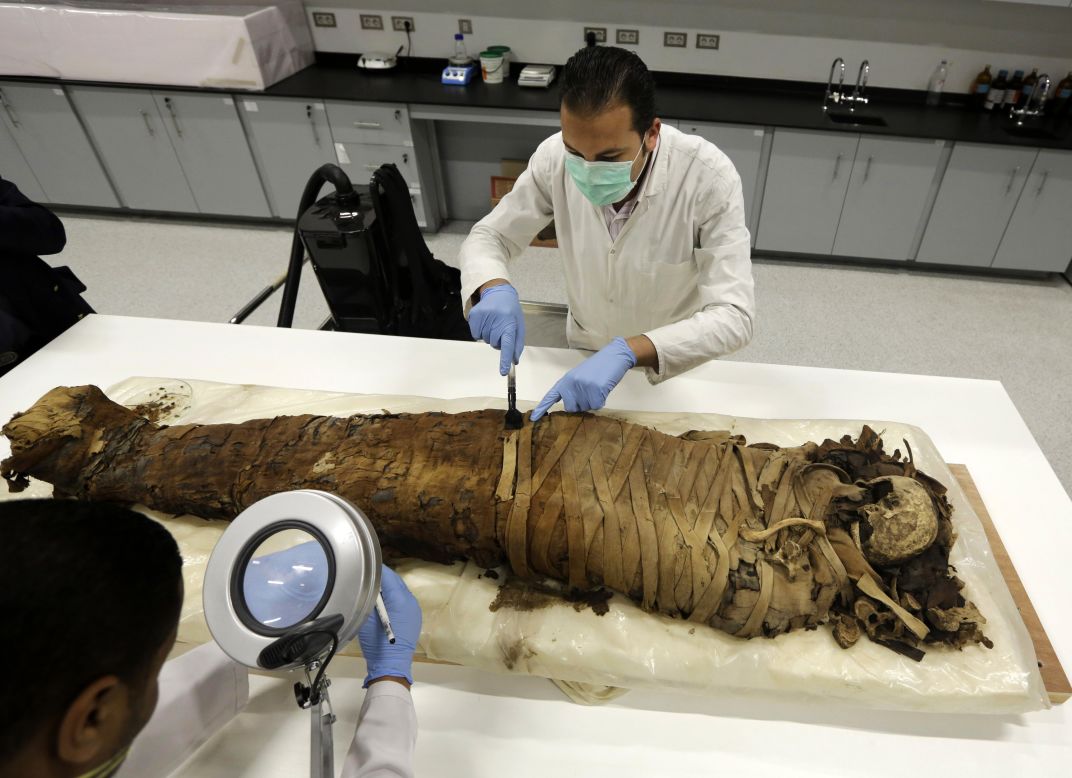 Conservators clean a female mummy dated to Pharaonic late period, between 712-323 BC, in the conservation center of Egypt's Grand Museum just outside of Cairo on Monday, March 17.