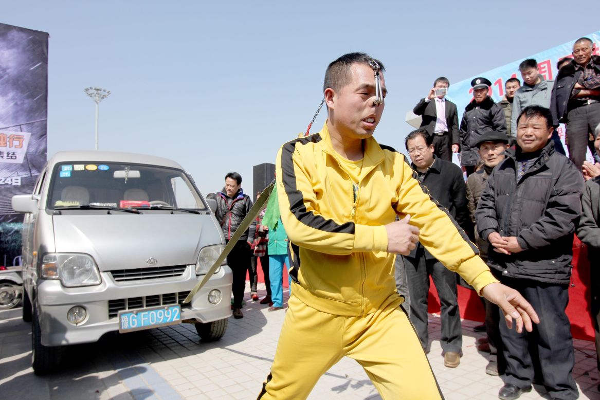 Stuntman Zhang Yilong pulls a van by his nostrils during an auto show in Zhoukou, China, on Friday, March 14. 