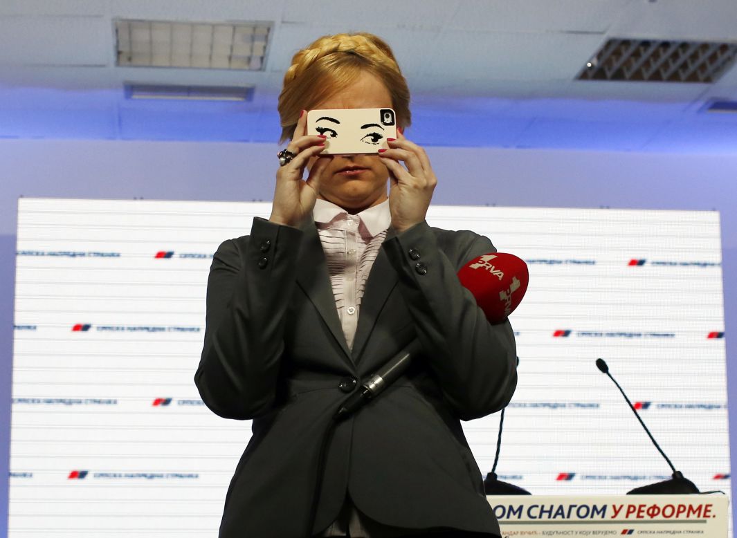 A television host takes photos with her cell phone at the headquarters of Serbia's Progressive Party on Sunday, March 16, in Belgrade.