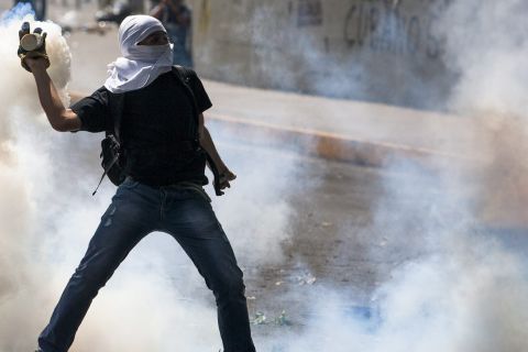 A person holds a smoking canister as demonstrators clash with members of the National Police on March 20 in Caracas. 