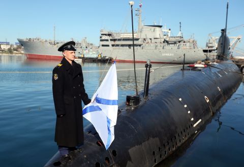 A Russian sailor holds the Russian Navy's St. Andrew's flag while standing on the bow of the surrendered Ukrainian submarine Zaporozhye on March 22 in Sevastopol.