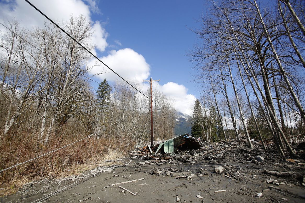 Downed power lines and parts of a destroyed house can be seen in the debris blocking the road near Oso on March 23.